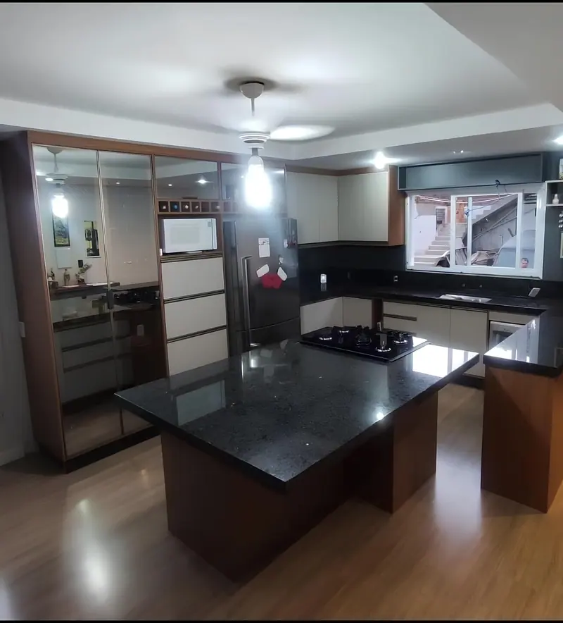 Cozinha planejada com ilha de granito preto, armários claros e prateleiras espelhadas