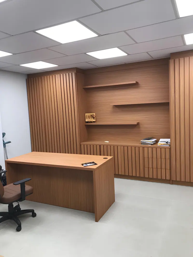 Escritório com mesa em madeira, painel ripado e prateleiras na parede