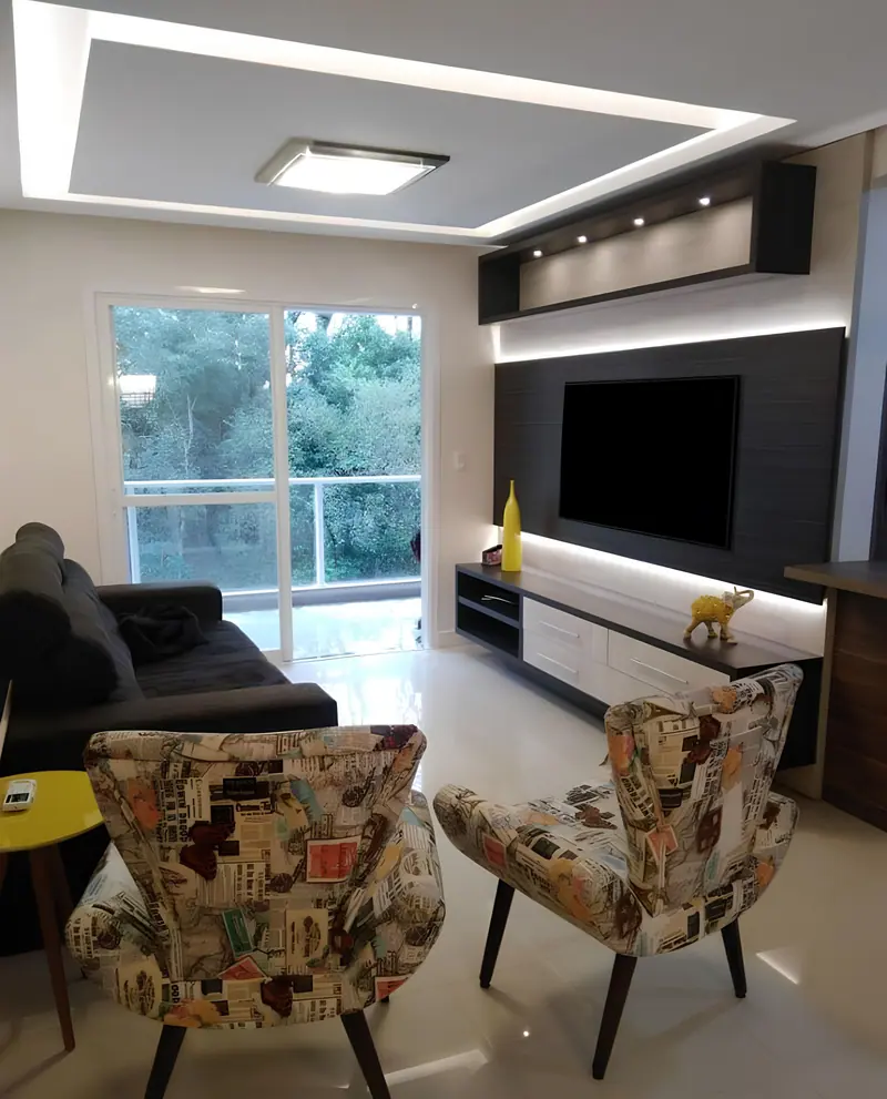 Sala de estar com home theater escuro, rack branco iluminado e sanca com LED